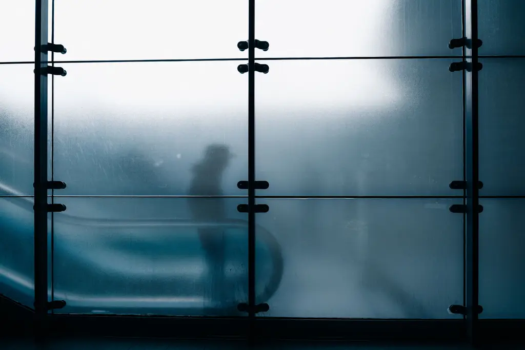 Silhouet van een voorbijganger achter matglas